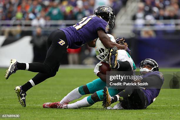 Running back Jay Ajayi of the Miami Dolphins is tackled by cornerback Jimmy Smith and free safety Lardarius Webb of the Baltimore Ravens in the...