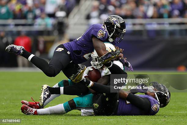 Running back Jay Ajayi of the Miami Dolphins is tackled by cornerback Jimmy Smith and free safety Lardarius Webb of the Baltimore Ravens in the...