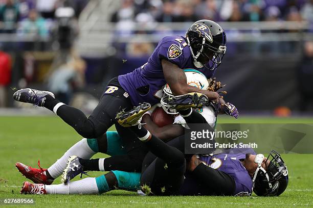 Running back Jay Ajayi of the Miami Dolphins is tackled by cornerback Jimmy Smith and free safety Lardarius Webb of the Baltimore Ravens in the...