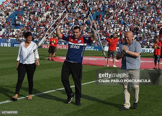 Uruguayan-Colombian former goalkeeper Alexis Viera waves holding his crutches during an homage before the start of the Nacional vs Juventud Las...
