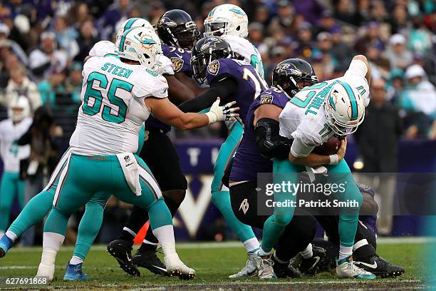 Quarterback Ryan Tannehill of the Miami Dolphins is sacked by defensive end Brent Urban of the Baltimore Ravens in the fourth quarter at M&T Bank...