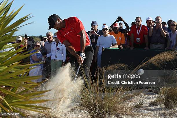Tiger Woods hits his second shot on the 18th hole from the out-of-bounds waste area as a gallery of fans look on during the final round of the Hero...