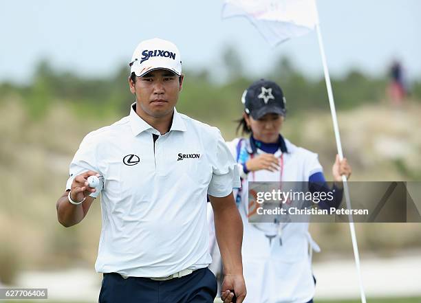 Hideki Matsuyama of Japan waves alongside caddie Mei Inui on the first hole during the final round of the Hero World Challenge at Albany, The Bahamas...