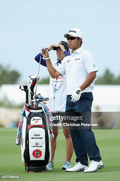 Hideki Matsuyama of Japan pulls a club alongside caddie Mei Inui on the first hole during the final round of the Hero World Challenge at Albany, The...