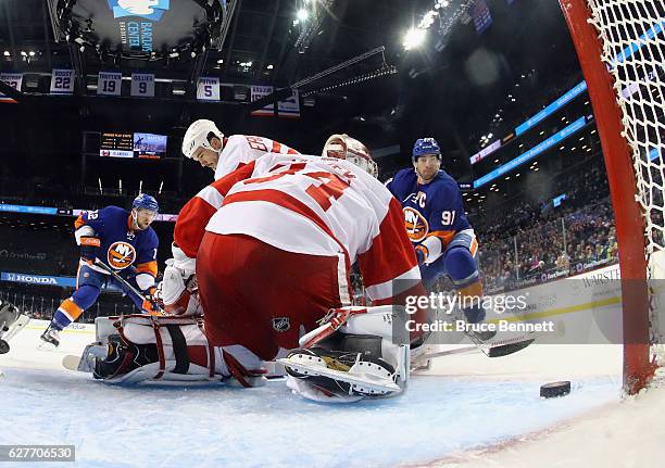 Josh Bailey and John Tavares of the New York Islanders converge on Petr Mrazek of the Detroit Red Wings during the first period at the Barclays...