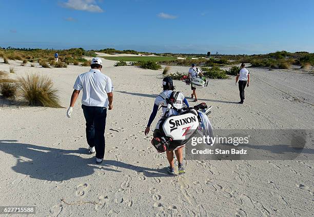 Hideki Matsuyama of Japan and caddie Mei Inui walk along the 16th hole during the final round of the Hero World Challenge at Albany course on...
