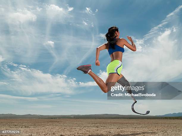 asian women with prosthetic leg running in the desert - amputatie stockfoto's en -beelden