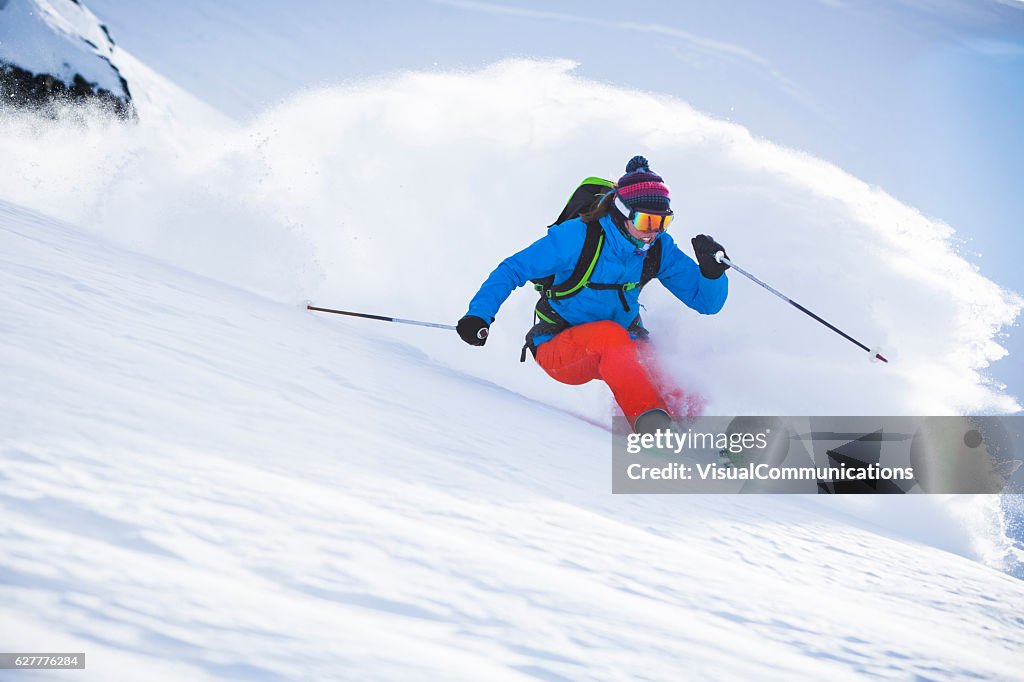 Female athlete skiing in deep powder.
