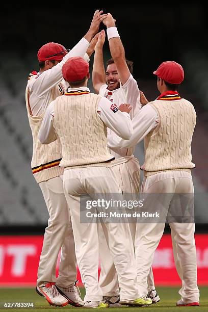 Chadd Sayers of the SA Redbacks celebrates with teammates after getting the wicket of Peter Nevill of the NSW Blues during day one of the Sheffield...