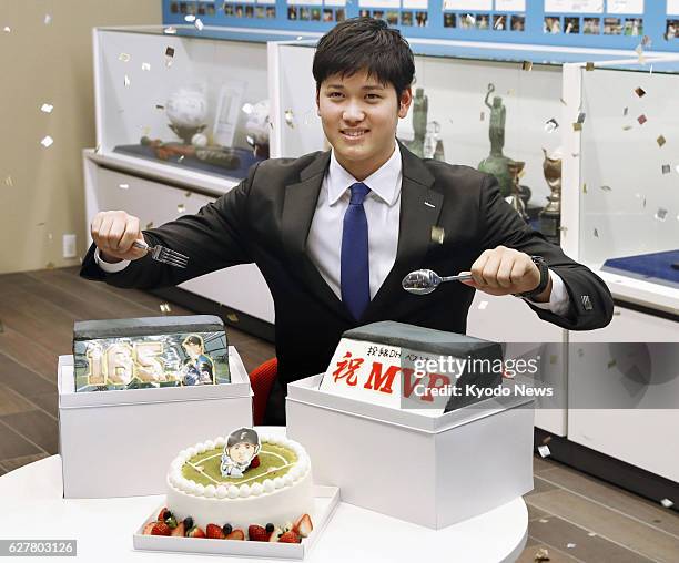 Nippon Ham Fighters pitcher-designated hitter Shohei Otani poses for a photo in front of cakes given by reporters in Sapporo on Dec. 5 after...