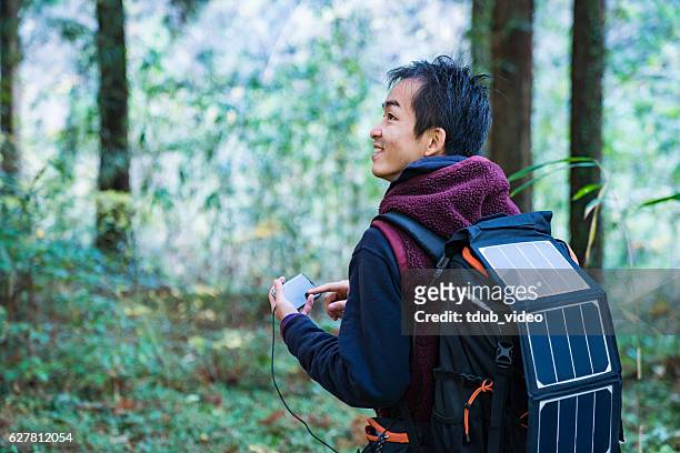 Man using solar cells to power smartphone in the forest