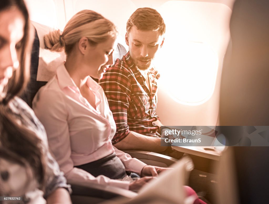 Young couple communicating while traveling by airplane.
