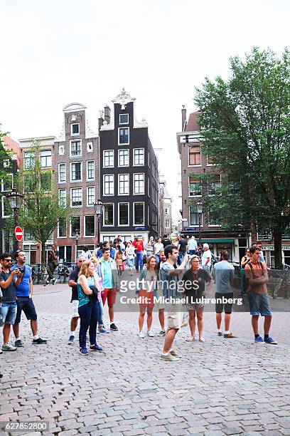 many tourists at canal and gracht vooburgwal - amsterdam gracht stockfoto's en -beelden
