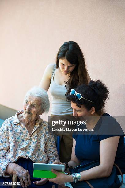 three women in discussion over photo memories on tablet - slavonia stock pictures, royalty-free photos & images