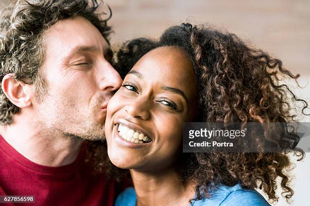close-up of man kissing cheerful woman on cheek - cheek kiss stock pictures, royalty-free photos & images