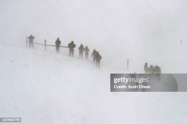 Despite blizzard conditions, activists watch from a hillside as military veterans march in support of the "water protectors" at Oceti Sakowin Camp on...