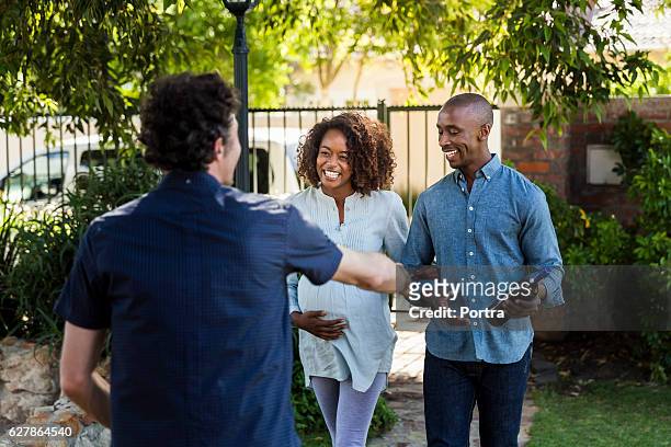 young couple greeting man during visit at yard - pregnant women greeting stockfoto's en -beelden
