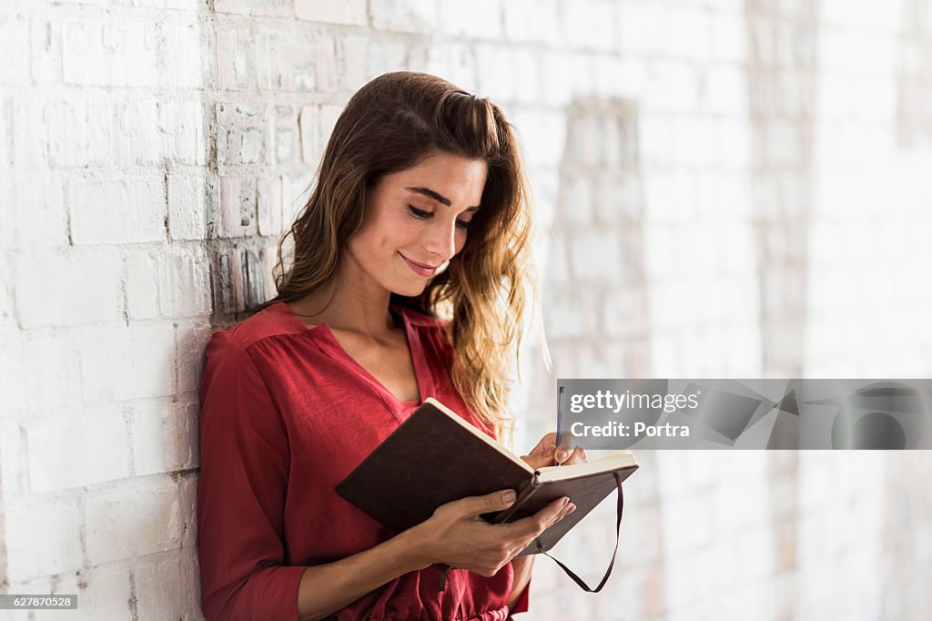 Smiling businesswoman writing in diary at office