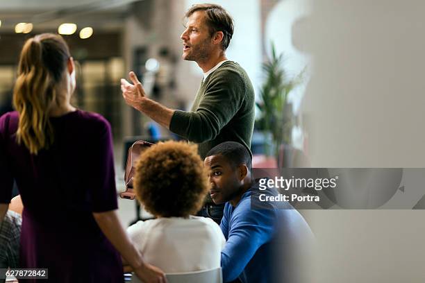 businessman talking to colleagues in meeting - informeel zakelijk stockfoto's en -beelden