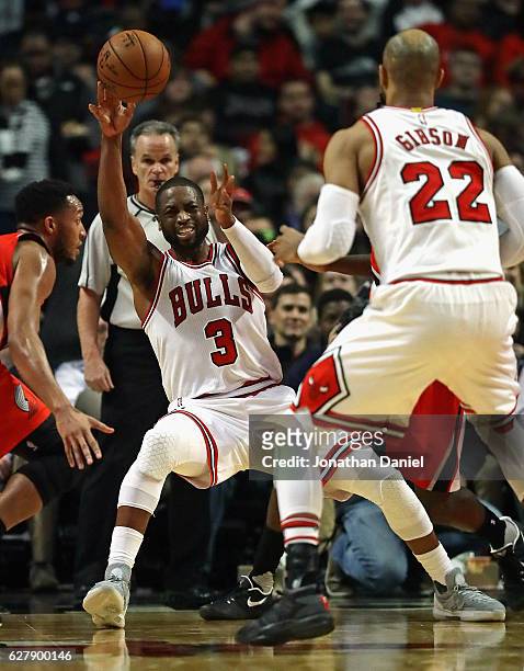 Dwyane Wade of the Chicago Bulls slips as he passes to Taj Gibson against the Portland Trail Blazers at the United Center on December 5, 2016 in...