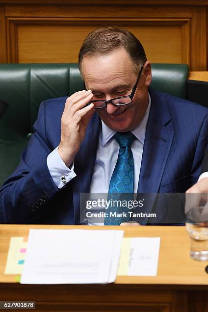 Prime Minister John Key checks his phone during the house session on December 6, 2016 in Wellington, New Zealand. Prime Minister John Key announced...