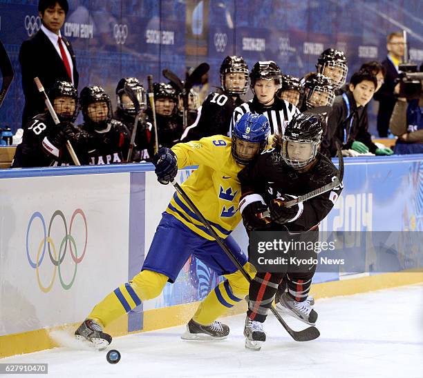 Russia - Japan forward Ami Nakamura fights for the puck during the first period of a Group B preliminary game against Sweden in women's ice hockey at...