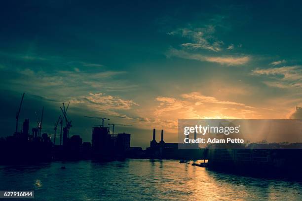 wachstum und entwicklung auf der londoner skyline bei sonnenuntergang - battersea power station silhouette stock-fotos und bilder