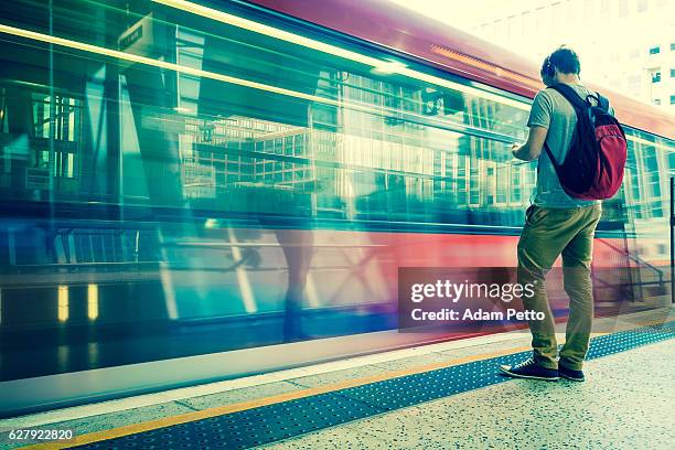 young man with backpack and headphones waiting for train - london underground speed stock pictures, royalty-free photos & images