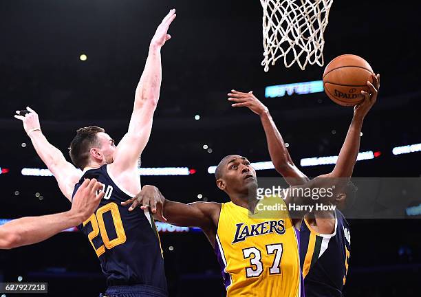 Metta World Peace of the Los Angeles Lakers scores between Gordon Hayward and Rodney Hood of the Utah Jazz during the first half at Staples Center on...