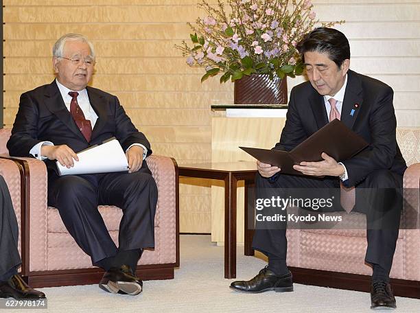 Japan - Prime Minister Shinzo Abe looks through a petition signed by Hiromasa Yonekura , chairman of Japan's most influential business lobby...