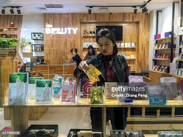 Girl is choosing facial mask in a shop selling Korean cosmetics and personal care commodities. Commercial relationship between China and South...