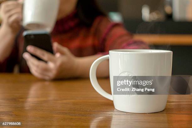 Starbucks coffee cup on table, beside which a customer is reading on mobile phone. At the end of November, a Chinese customer posted an open letter...