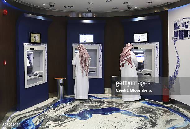 Customers use automated teller machines inside the Al Rajhi Bank in Riyadh, Saudi Arabia, on Thursday, Dec. 1, 2016. Saudi Arabia is working to...