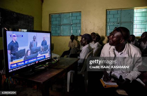 Residents watch the screening of the start of the ICC trial of former child soldier-turned-warlord Dominic Ongwen in Lukodi, Uganda on December 6,...