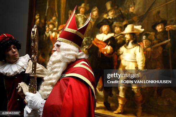 Man dressed as Sinterklaas and other in Zwarte Piet stand on December 6, 2016 in front of the 'De Nachtwacht' by Dutch painter Rembrandt during their...