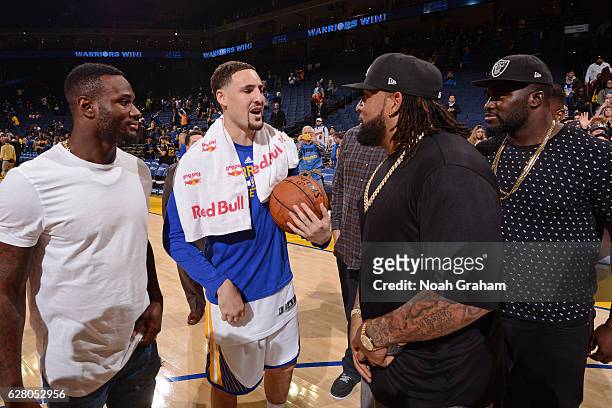 Klay Thompson of the Golden State Warriors talks to Oakland Raiders, Latavious Murray and Donald Penn after the game against the Indiana Pacers on...
