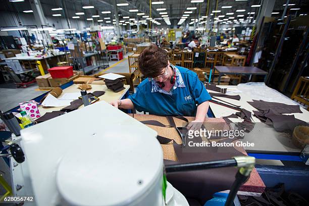 Factory worker Pat Derocher uses a die cutting machine to cut patterns to sewn together as Bean boots at the LL Bean factory in Brunswick, ME on May...
