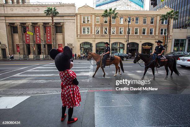 Los Angeles Police Department Mounted Platoon officers ride past a Minnie Mouse character near the Jimmy Kimmel Live studio on Hollywood Boulevard as...