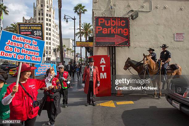 Group of evangelizing Christians marches past Los Angeles Police Department Mounted Platoon officers on Hollywood Boulevard as police and deputies...