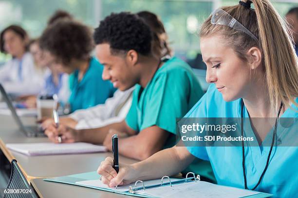 focus medical students take notes during lecture - medical scrubs bildbanksfoton och bilder