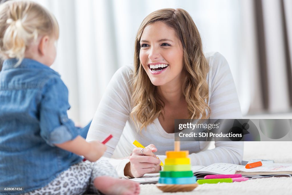 Happy mom plays with toddler daughter at home