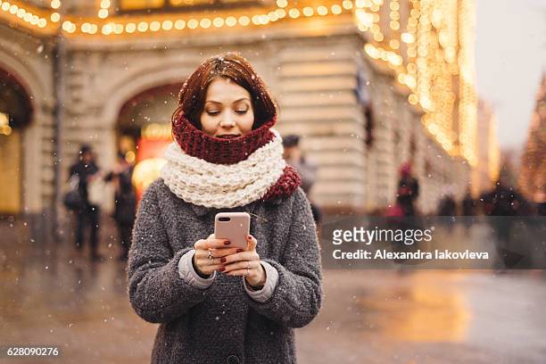 frau mit handy auf der straße - winter woman phone stock-fotos und bilder