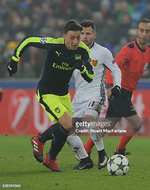 Mesut Ozil of Arsenal breaks past Renato Steffen of Basel during the UEFA Champions League match between FC Basel and Arsenal at St. Jakob-Park on...