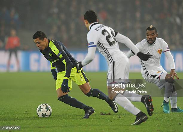 Alexis Sanchez of Arsenal takes on Mohamed Elyounoussi and Geoffroy Serey of Basel during the UEFA Champions League match between FC Basel and...