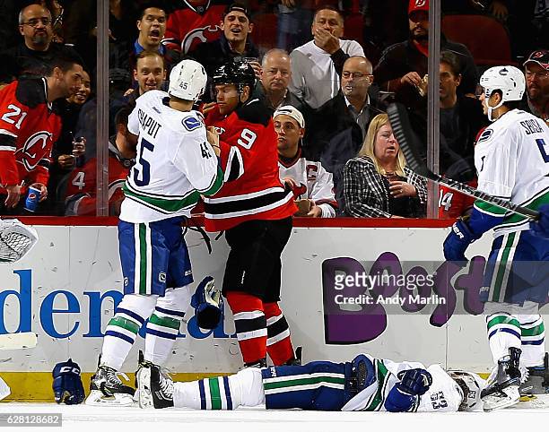 Taylor Hall of the New Jersey Devils and Michael Chaput of the Vancouver Canucks come together after Taylor Hall checks Philip Larsen to the ice...