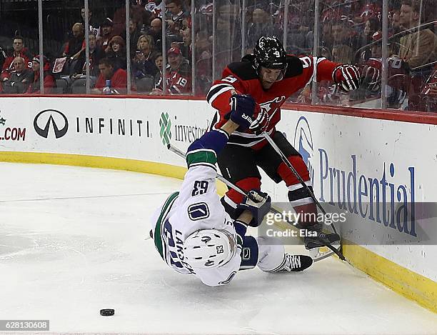 Taylor Hall of the New Jersey Devils hits Philip Larsen of the Vancouver Canucks in the second period on December 6, 2016 at Prudential Center in...