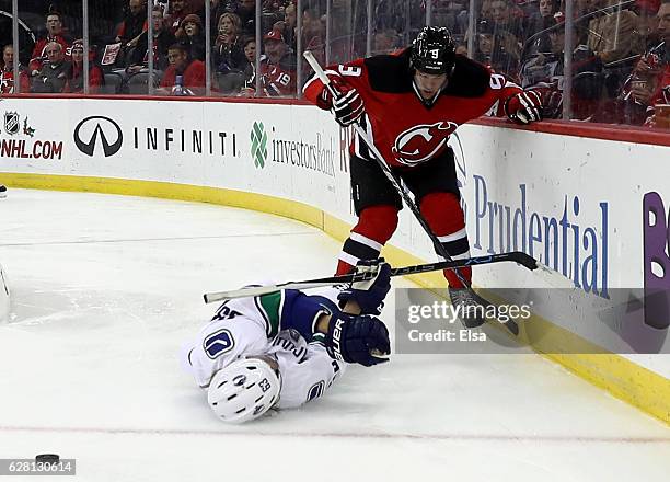 Taylor Hall of the New Jersey Devils hits Philip Larsen of the Vancouver Canucks in the second period on December 6, 2016 at Prudential Center in...