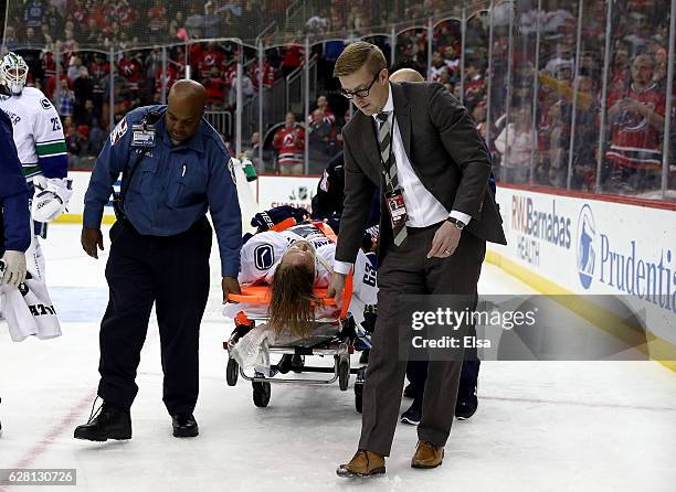 Philip Larsen of the Vancouver Canucks is carried off the ice on a stretcher after he was hit by Taylor Hall of the New Jersey Devils in the second...