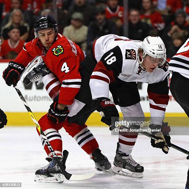 Christian Dvorak of the Arizona Coyotes gets tangled up with Niklas Hjalmarsson of the Chicago Blackhawks at the United Center on December 6, 2016 in...