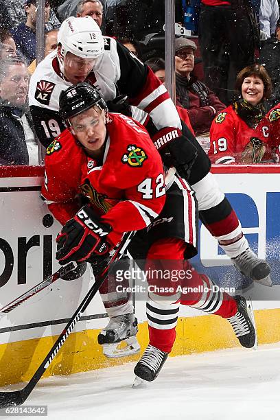 Gustav Forsling of the Chicago Blackhawks and Shane Doan of the Arizona Coyotes get physical by the glass in the first period at the United Center on...